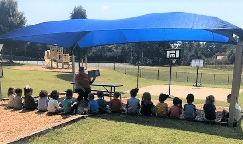 A teacher reading outside with kids